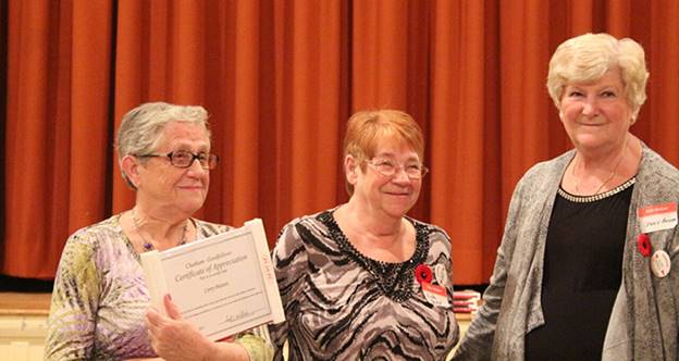 Corry Putters receives a certificate of achievement from Linda Haskell and Judy Bagley.